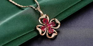 신사일주 썸네일 이미지 - jewelry-625725_640 루비가 꽃모양으로 생긴 보석 목걸이가 녹색 천 위에 놓여 있습니다.